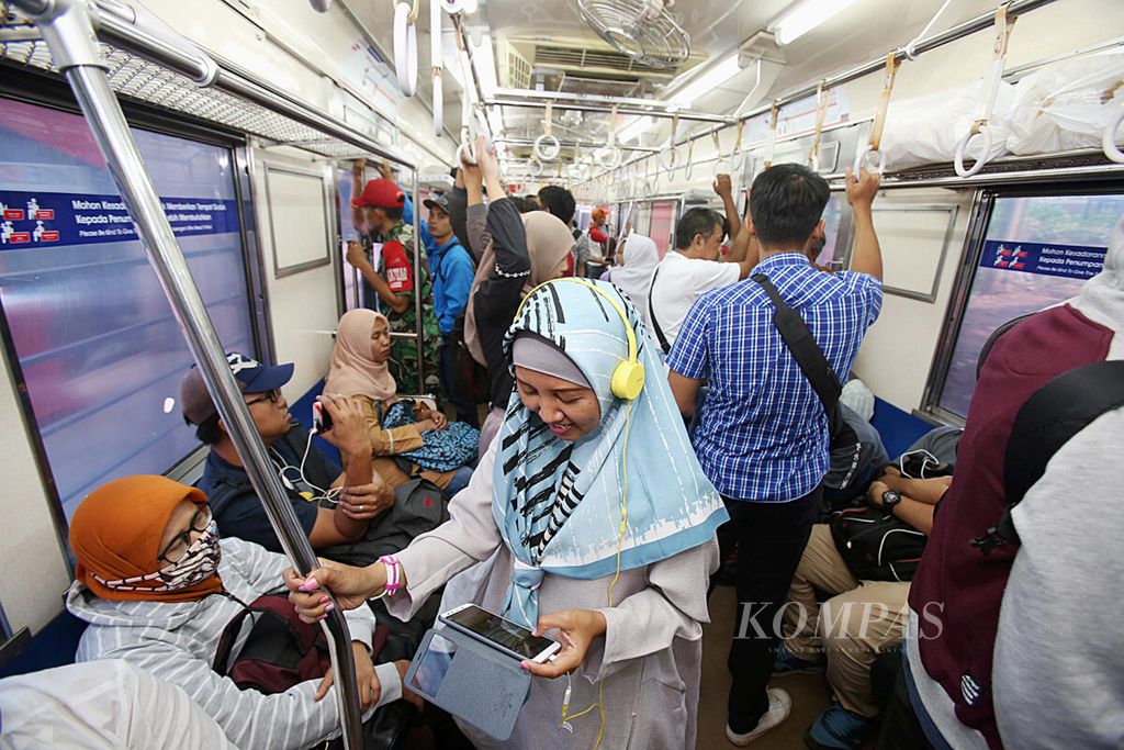 Ilustrasi: Rizqi memasang earphone lalu memutar drama Korea di ponselnya selama perjalanan di kereta komuter, Jakarta, Jumat (7/12/2018).