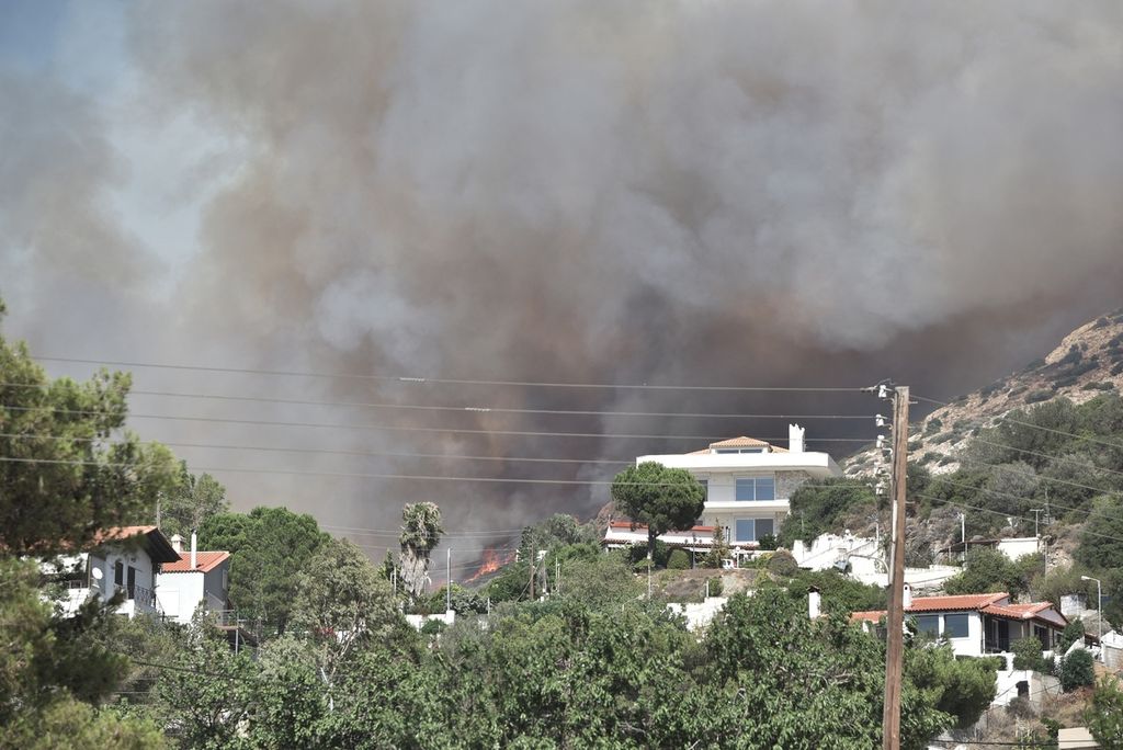 Asap akibat kebakaran lahan membubung di Kouvaras, sekitar 50 kilometer dari Athena, ibu kota Yunani, pada 17 Juli 2023. Cuaca panas ekstrem mengakibatkan percikan api di semak-semak yang kering.