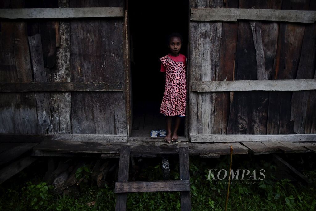  Seorang anak perempuan berdiri di depan pintu rumahnya di Kampung Kwau, 13 April 2021. 