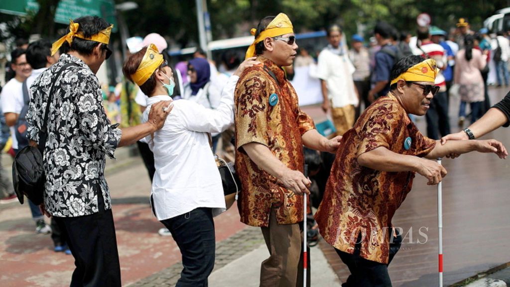 Penyandang disabilitas dituntun turun dari trotoar saat mengikuti aksi damai di depan Istana Merdeka, Jakarta, Kamis (18/5).