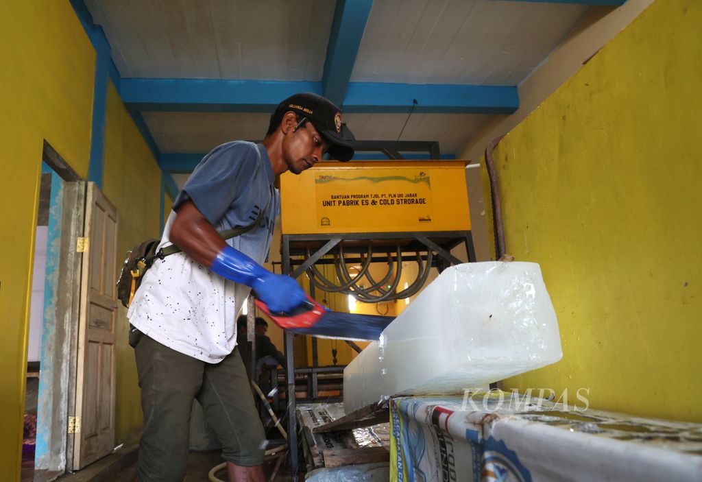 Pekerja memotong balok es menajdi dua bagian sebelum disimpan di mesin pendingin di Pabrik Es Bumdes Motekar, Desa Samudera Jaya, Kecamatan Caringin, Kabupaten Garut, Jawa Barat, Kamis (25/5/2023).
