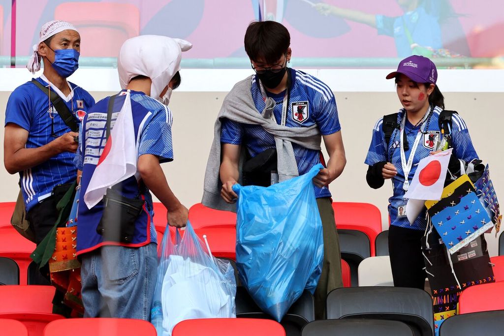 Suporter Jepang mengumpulkan sampah sebelum meninggalkan stadion usai pertandingan Grup E Piala Dunia Qatar antara Jepang dan Kosta Rika di Stadion Ahmad Bin Ali, Al Rayyan, Minggu (27/11/2022).