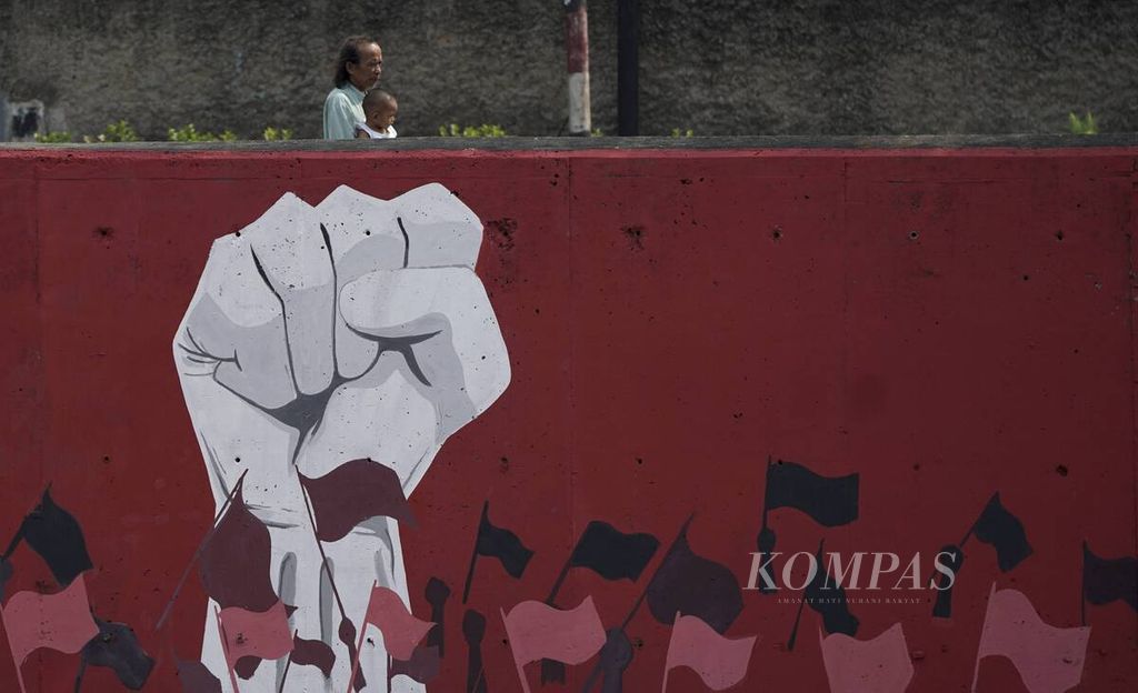 Warga melintasi mural bertemakan kemerdekaan di tanggul beton Sungai Ciliwung di Tebet, Jakarta Selatan, Minggu (9/8/2020). 