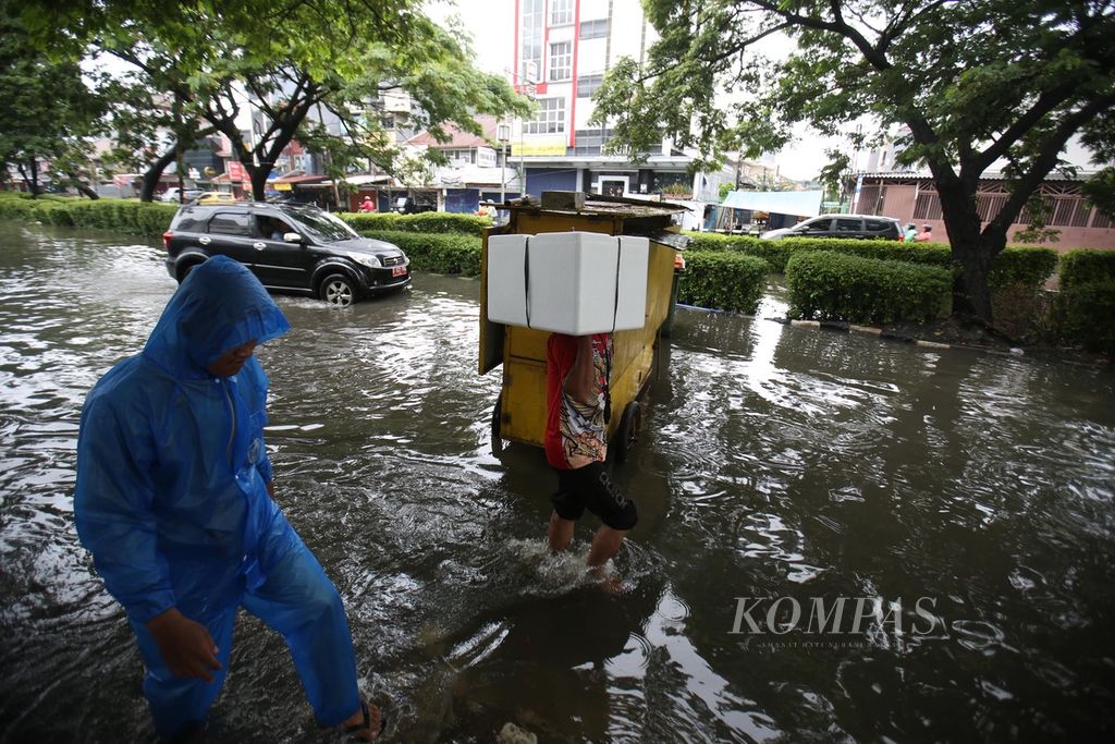 Warga berusaha melalui genangan banjir di kawasan Kelapa gading, Jakarta Utara, Jumat (22/3/2024). 