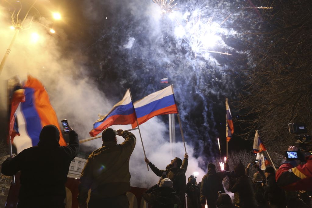People celebrate the recognizing the independence waving Russian national flag in the center of Donetsk, the territory controlled by pro-Russian militants, eastern Ukraine, late Monday, Feb. 21, 2022. In a fast-moving political theater, Russian President Vladimir Putin has moved quickly to recognize the independence of separatist regions in eastern Ukraine in a show of defiance against the West amid fears of Russian invasion in Ukraine.