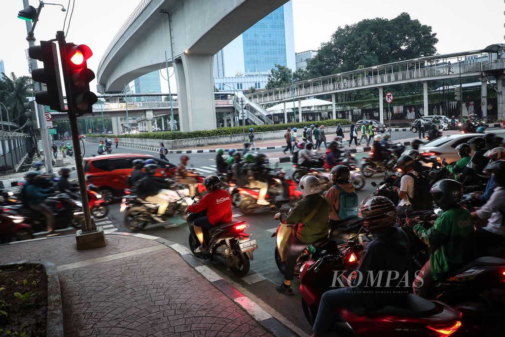 Pengendara sepeda motor menunggu lampu merah pada persimpangan jalan di kawasan Kuningan, Jakarta, Senin (3/7/2023).