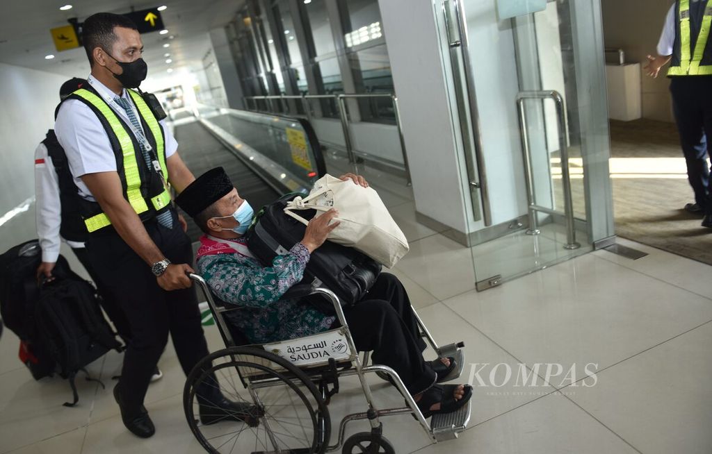Petugas mendorong kursi roda yang membawa calon jemaah haji kloter 1 Jawa Timur kesulitan berjalan di Terminal 2 Bandara Juanda Surabaya di Sidoarjo, Jawa Timur, Sabtu (4/6/2022). 