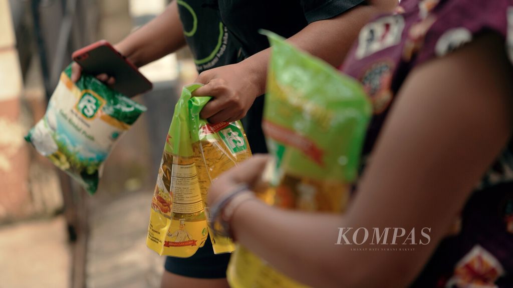 Warga membawa kemasan minyak goreng dalam pasar murah yang diadakan oleh Food Station di Kantor Kelurahan Pondok Kopi, Duren Sawit, Jakarta Timur, Kamis (24/2/2022).