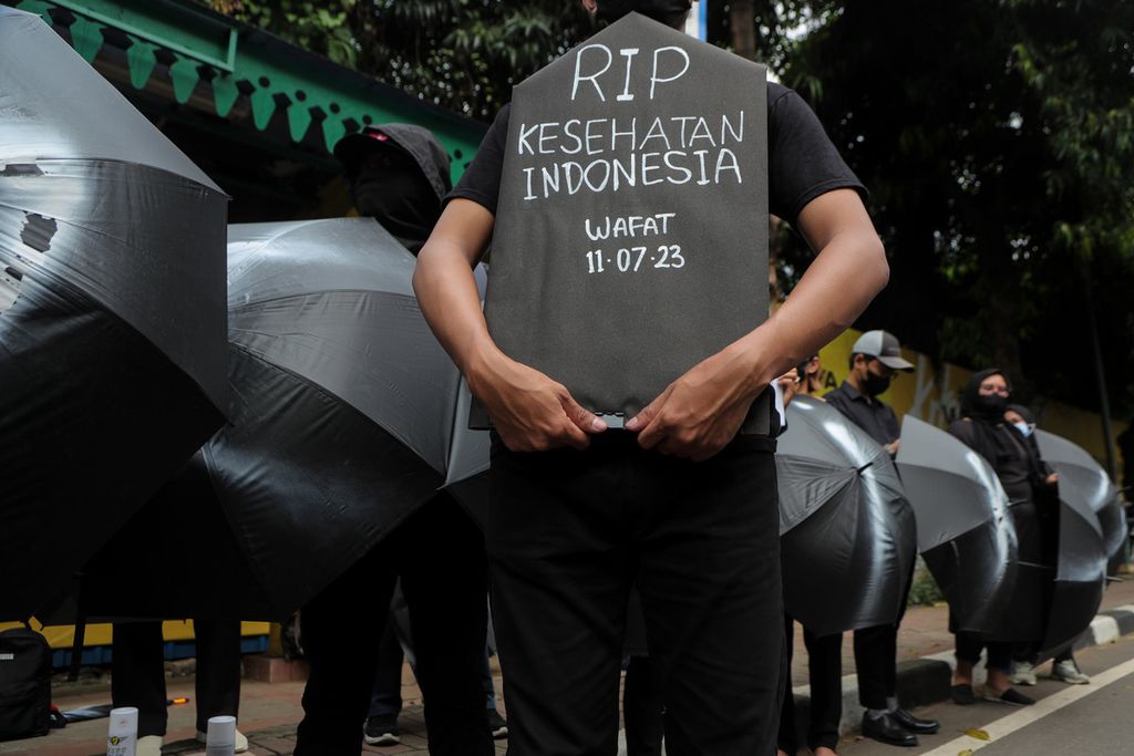 Peserta aksi mengangkat replika papan pusara bertuliskan ungkapan rasa duka atas disahkannya UU Kesehatan saat aksi di Jalan HR Rasuna Said, Jakarta Selatan, Jumat (14/7/2023). 