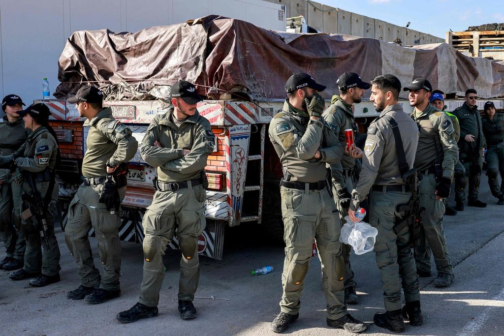  Pasukan keamanan Israel berjaga di dekat salah satu truk Mesir yang membawa pasokan bantuan kemanusiaan ke Jalur Gaza dari perbatasan Kerem Shalom yang melintasi wilayah Palestina pada 6 Februari 2024.