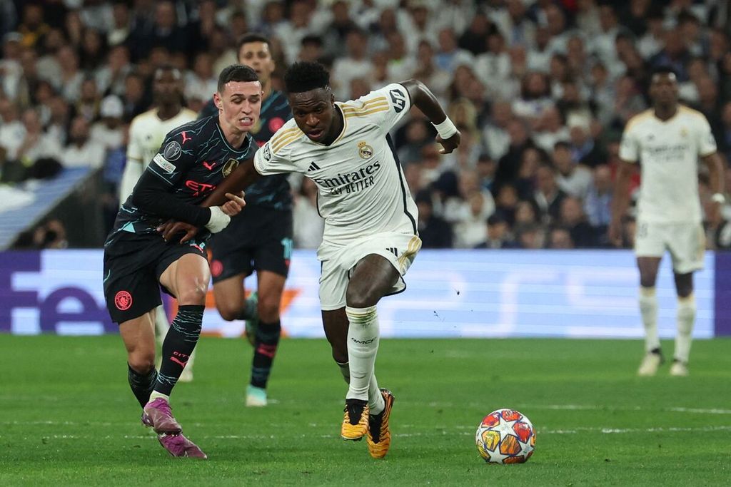 Manchester City player Phil Foden (left) vies for the ball with Real Madrid player Vinicius Junior in the first leg of the Champions League quarterfinals at Santiago Bernabeu Stadium in Madrid, Spain on Tuesday (9/4/2024).