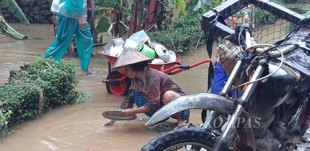 Salah satu warga Dusun Rowotrate, Desa Sitiarjo, Kecamatan Sumbermanjing Wetan, Kabupaten Malang, Jawa Timur, membersihkan peralatan dapur yang terdampak banjir menggunakan air sisa-sisa banjir di tepi jalan, Selasa (18/10/2022).