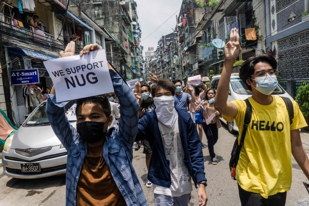 Seorang pengunjuk rasa membawa poster berisi dukungan pada kelompok Pemerintahan Persatuan Nasional atau National Unity Government (NUG) dalam demonstrasi menentang kudeta militer di Sanchaung, Yangoon, Myanmar, 27 April 2021. 