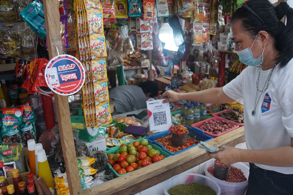 Petugas memajang kode respons cepat standar Indonesia (QRIS) di lapak milik Vera Tulung (52) di Pasar Tanawangko, Minahasa, Sulawesi Utara, Jumat (5/11/2021).