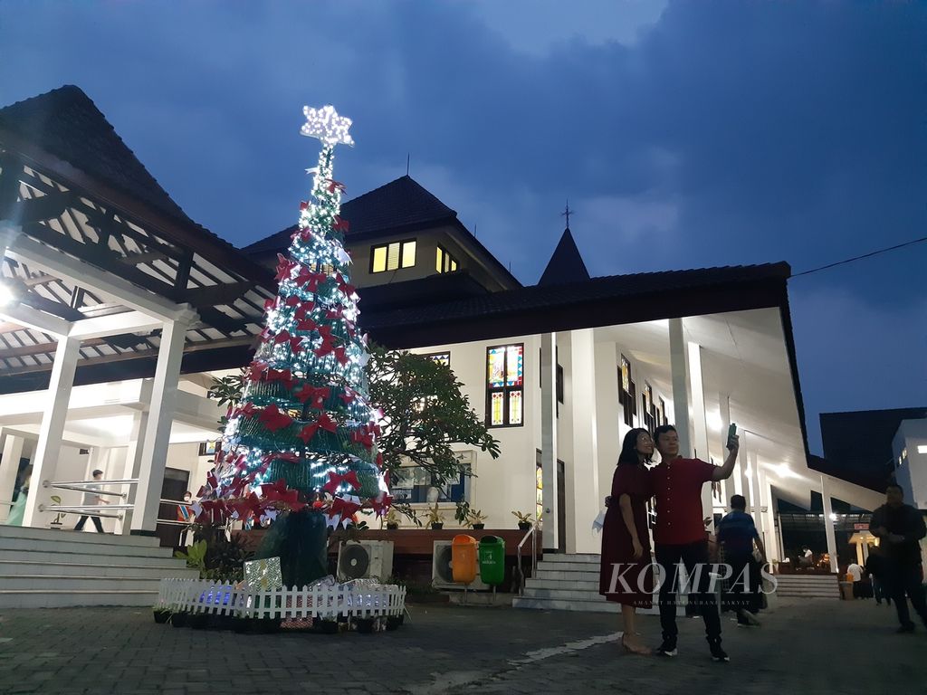 Warga berfoto dengan latar pohon natal di Gereja Paroki Bunda Maria, Kota Cirebon, Jawa Barat, Sabtu (24/12/2022). 