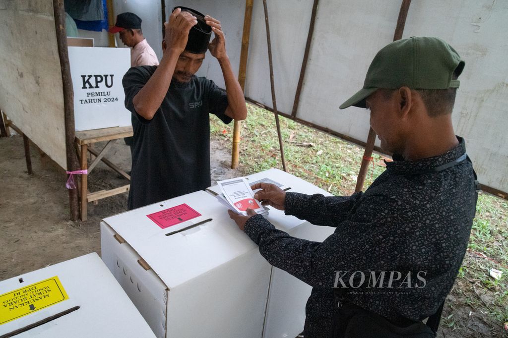 Petugas tempat pemungutan suara membantu warga memasukkan surat suara ke dalam kotak suara di Kampung Pasir Panjang, Pulau Rempang, Batam, Kepulauan Riau, Rabu (14/2/2024).