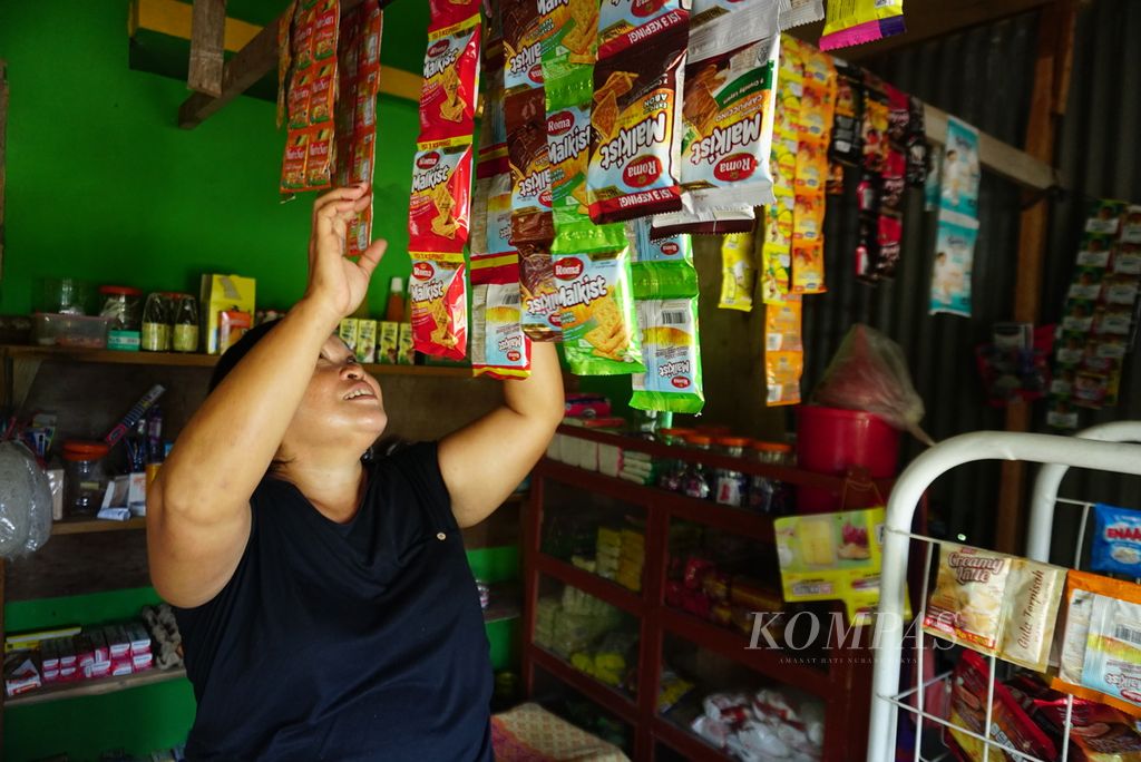 Nova Kalompo merapikan baraang-barang dagangan di toko yang terletak di pekarangan rumahnya di Desa Mangkit, Kecamatan Belang, Minahasa Tenggara, Sulawesi Utara, Rabu (10/1/2024). 