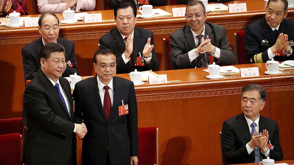 Presiden China  Xi Jinping (kiri) berjabat tangan dengan Perdana Menteri Li Keqiang saat anggota delegasi bertepuk tangan setelah Li terpilih kembali  dalam sidang Parlemen China, Minggu (18/3). Sehari sebelumnya, Xi juga kembali terpilih sebagai Presiden China. 