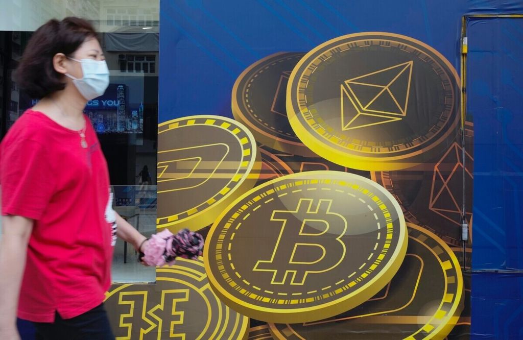 Seorang perempuan berjalan melewati iklan tentang mata uang kripto Bitcoin di Hong Kong, 1 Juni 2021. 