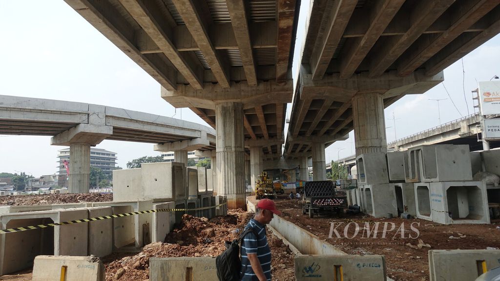 Warga melewati proyek gerbang tol Becakayu di Cipinang Besar Utara, Jakarta Timur, Minggu (10/4/2022). Jalan Tol Bekasi-Cawang-Kampung Melayu (Becakayu) sampai seksi 2A Bekasi Barat ditargetkan selesai Juni 2022. 
