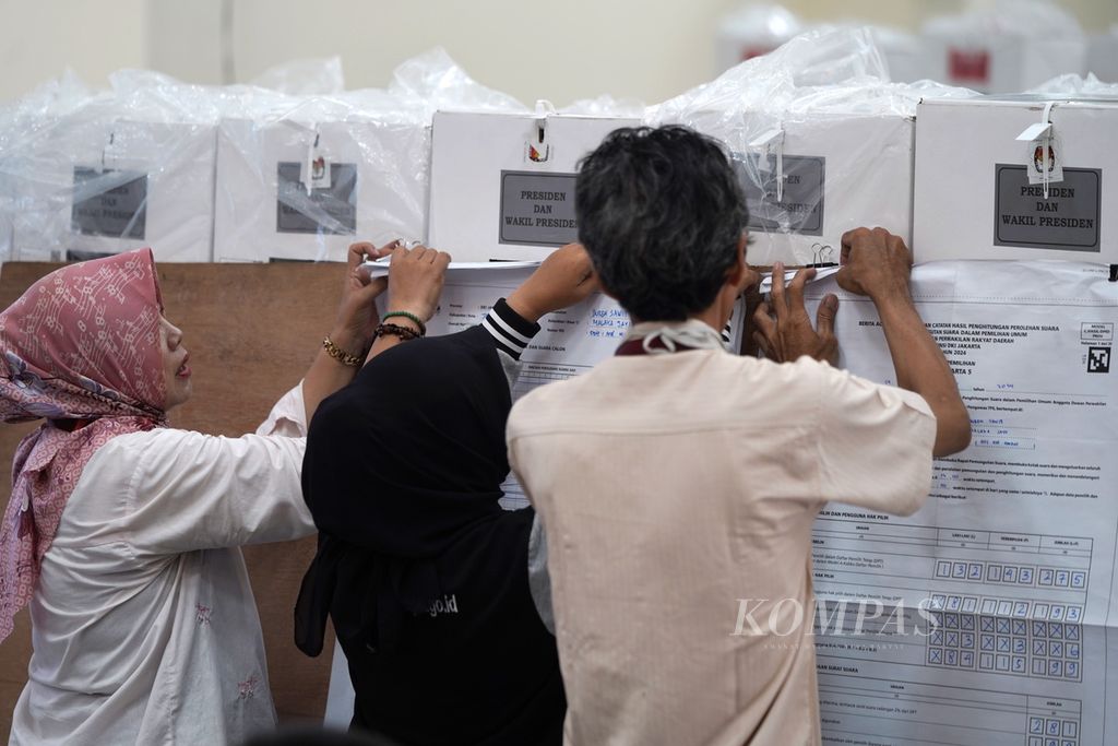 Anggota Panitia Pemilihan Kecamatan (PPK) menempelkan lembaran hasil penghitungan suara TPS untuk dicatat dalam rekapitulasi hasil penghitungan suara tingkat kecamatan di GOR Duren Sawit, Jakarta Timur, Sabtu (17/2/2024). 
