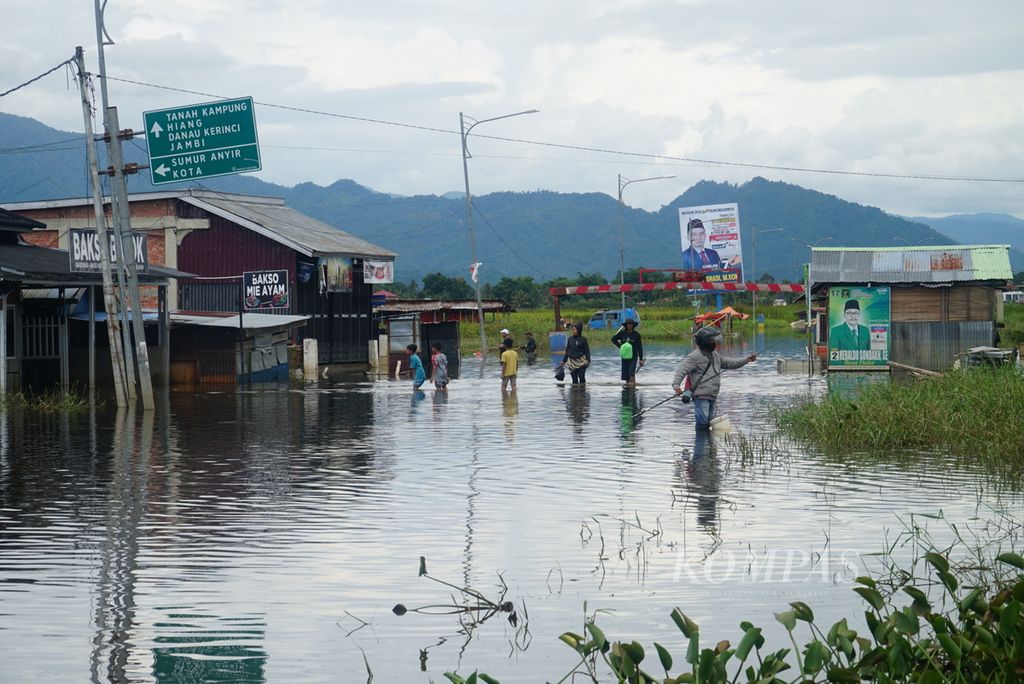 Aktivitas warga di Jalan Pancasila dekat Jembatan Kerinduan yang terendam banjir di Desa Lawang Agung, Kota Sungai Penuh, Jambi, Sabtu (20/1/2024). 