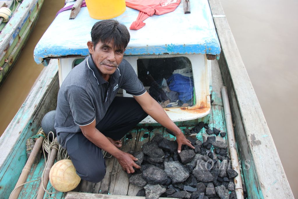 Muslim, nelayan tradisional di Kecamatan Meureubo, Kabupaten Aceh Barat, Aceh, Minggu (16/10/2023), memperlihatkan batubara yang terbawa saat ia menjaring ikan di perairan Meureubo itu.