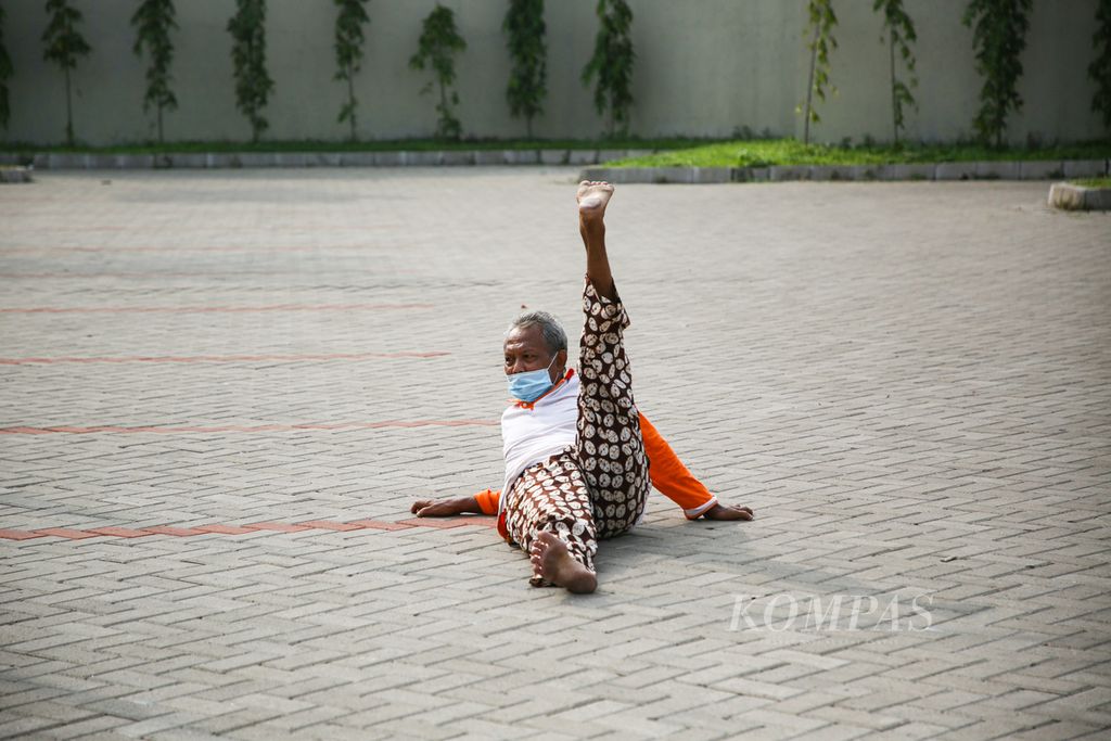 Seorang lanjut usia menggerakkan kakinya sambil berjemur di area parkir gedung pertemuan di kawasan Larangan, Kota Tangerang, Banten, Jumat (4/6/2021). 
