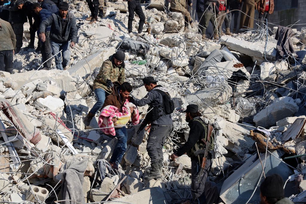 Seorang laki-laki membawa tubuh anak kecil yang diambil dari reruntuhan gedung di Harim, Suriah, yang berbatasan dengan Turki, Rabu (8/2/2023). Pada 6 Februari, daerah ini diguncang gempa M 7,8 yang menewaskan lebih dari 8.000 jiwa.
