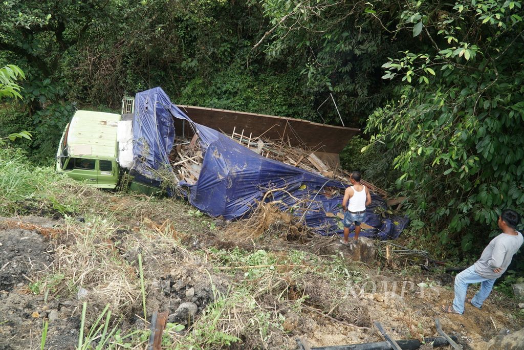 Sopir dan temannya mengamati kondisi truk pengangkut besi tua yang masuk jurang di sekitar Panorama II Jalur Sitinjau Lauik, Kota Padang, Sumatera Barat, Kamis (5/1/2023). 