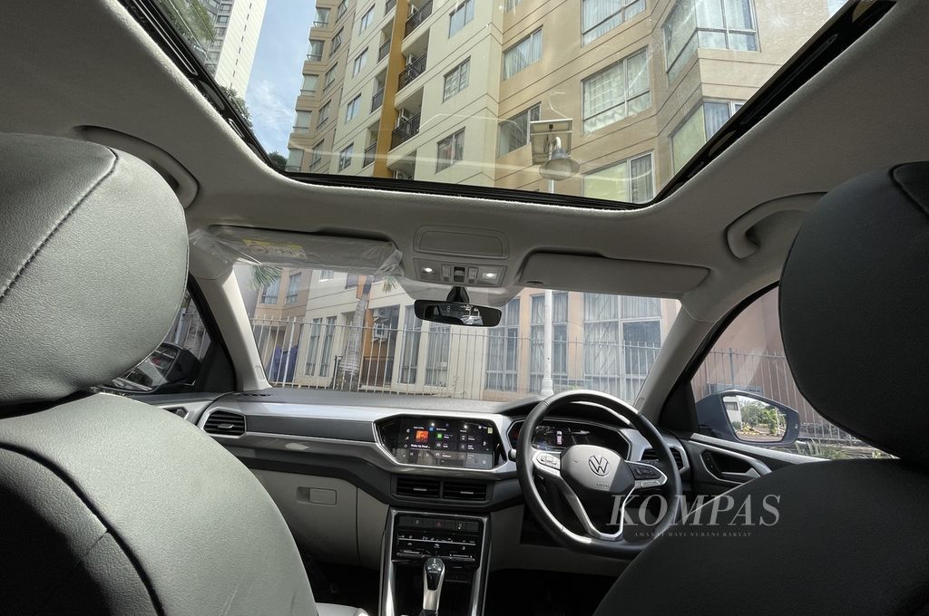 Kabin VW T-Cross dilihat dari baris kedua. Tampak desain dasbornya terlihat rapi dan simpel. Mobil berjenis SUV berukuran subkompak ini juga menggunakan atap kaca yang dapat dibuka di bagian depan.