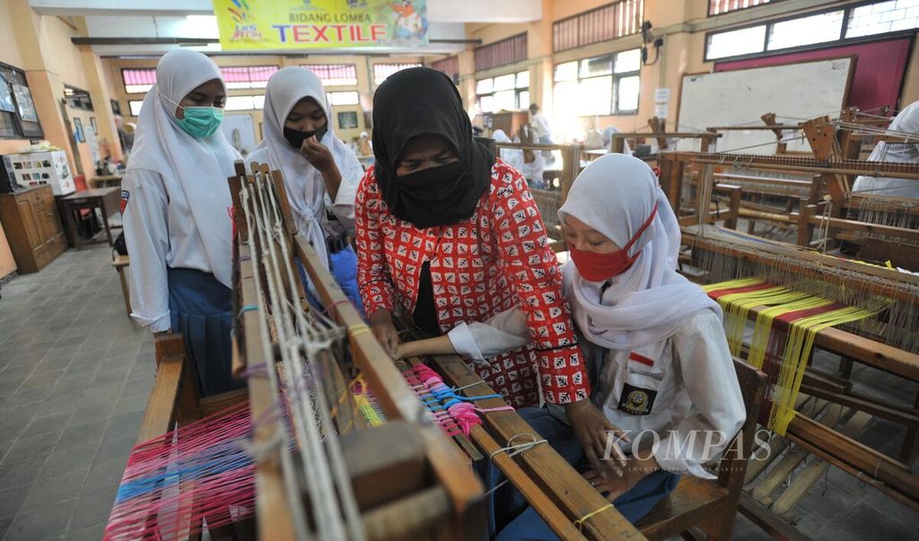 Guru mengajar siswa Jurusan Kria Tekstil SMK Negeri 12 Surabaya, Jatim, menenun, Rabu (2/9/2020). Sekolah menengah kejuruan seni tersebut kembali menyelenggarakan sekolah tatap muka dan memberlakukan sistem sekolah bergilir bagi siswanya. 