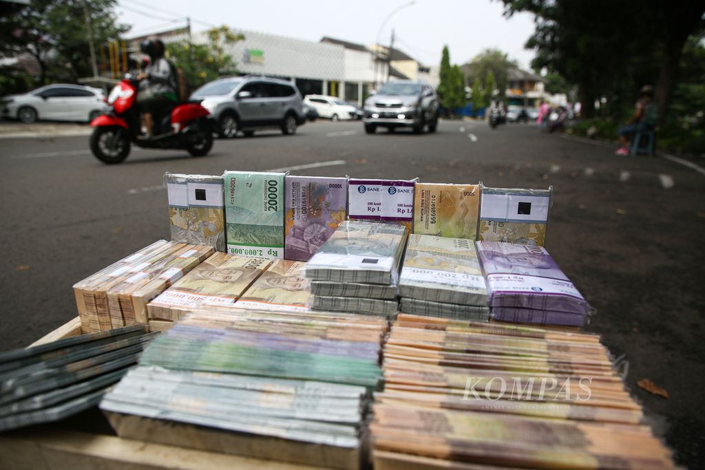 Tumpukan uang baru dipajang penjual jasa penukaran uang untuk menarik minat warga yang melintas di pinggir Jalan Bintaro Utama Raya, Pesanggrahan, Jakarta Selatan, Kamis (6/5/2021). Uang baru pecahan Rp 2.000, Rp 5.000, dan Rp 10.000 banyak dicari warga untuk angpau lebaran.