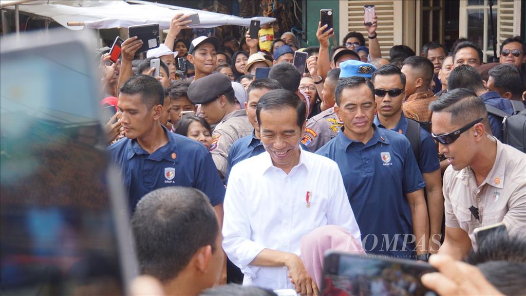 Presiden Joko Widodo dicium tangannya oleh seorang warga seusai berbelanja batik di Pasar Beringharjo, Yogyakarta, Minggu (8/6/2019).