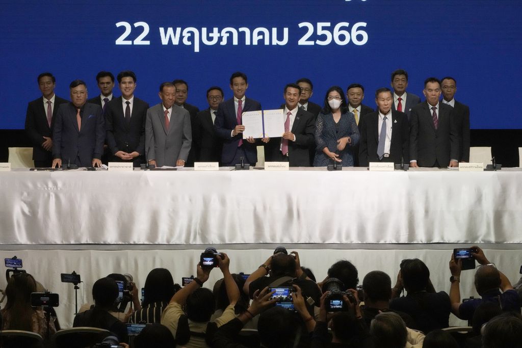 Ketua Partai Bergerak Maju Pita Limjaroenrat (kiri, tengah) dan Ketua Partai Pheu Thai Chonlanan Srikaew (kanan, tengah) memegang nota kesepahaman upaya membentuk pemerintahan koalisi antara Partai Bergerak Maju dan aliansi partai oposisi lain saat konferensi pers di Bangkok, Thailand, Senin (22/5/2023). 