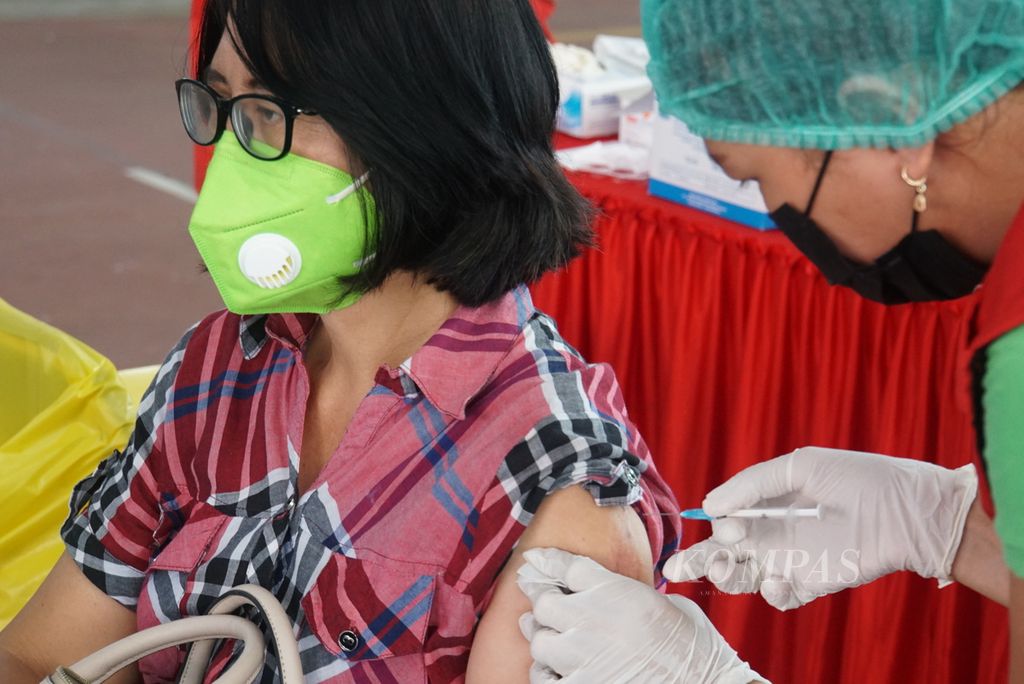Seorang wanita menerima suntikan vaksin Covid-19 bermerek AstraZeneca, Rabu (24/3/2021), dalam gelaran vaksinasi massal di Manado, Sulawesi Utara. Sulut menjadi salah satu daerah pertama yang menggunakan vaksin AstraZeneca.
