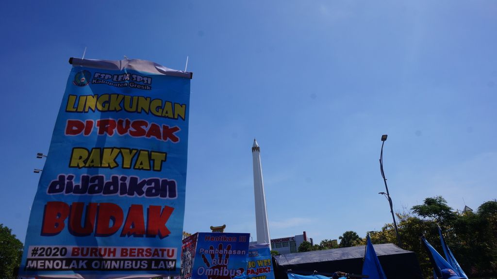 Spanduk yang dibawa oleh kalangan buruh saat demonstrasi menolak RUU Cipta Kerja di depan Kantor Gubernur Jawa Timur, Surabaya, Selasa (28/7/2020).