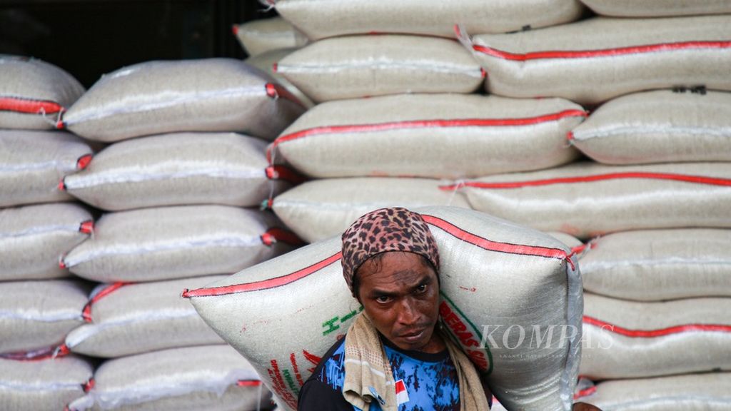 Buruh pikul bersiap memuat beras ke kendaraan pembeli di pasar induk beras Cipinang, Jakarta Timur, Kamis (15/12/2022).