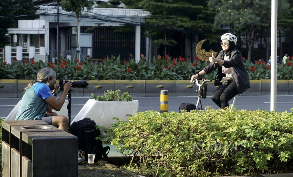 Pesepeda menyapa fotografer yang menjual jasa pemotretan ativitas olahraga di Jalan Sudirman, Jakarta, 8 Mei 2022. Pelonggaran aktivitas bersamaan meredanya pandemi Covid-19 disambut masyarakat yang ingin berolahraga.