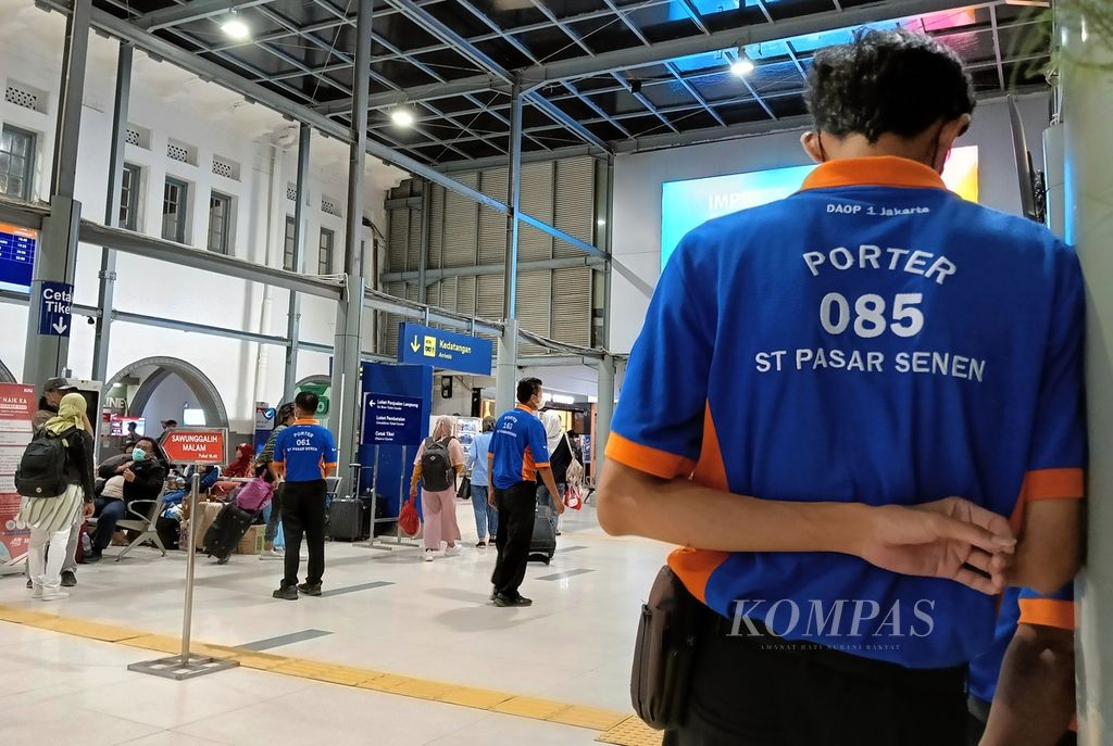 Seorang <i>porter</i> menunggu giliran untuk menawarkan jasa angkut barang kepada penumpang di Stasiun Pasar Senen, Kamis (9/3/2023).