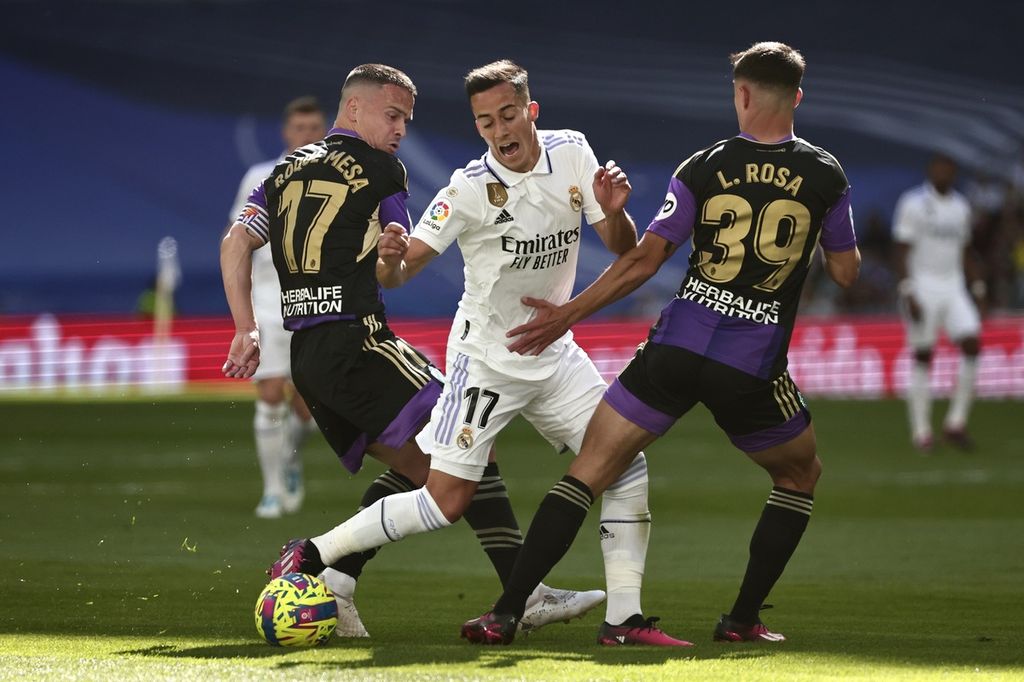 Pemain Real Madrid Lucas Vazquez (tengah) dikepung pemain Real Valladolid's Roque Mesa (kiri) dan Lucas Rosa (kanan) pada laga Liga Spanyol di Stadion Santiago Bernabeu, Madrid, Minggu (2/4/2023). Madrid menang 6-0 pada laga itu.