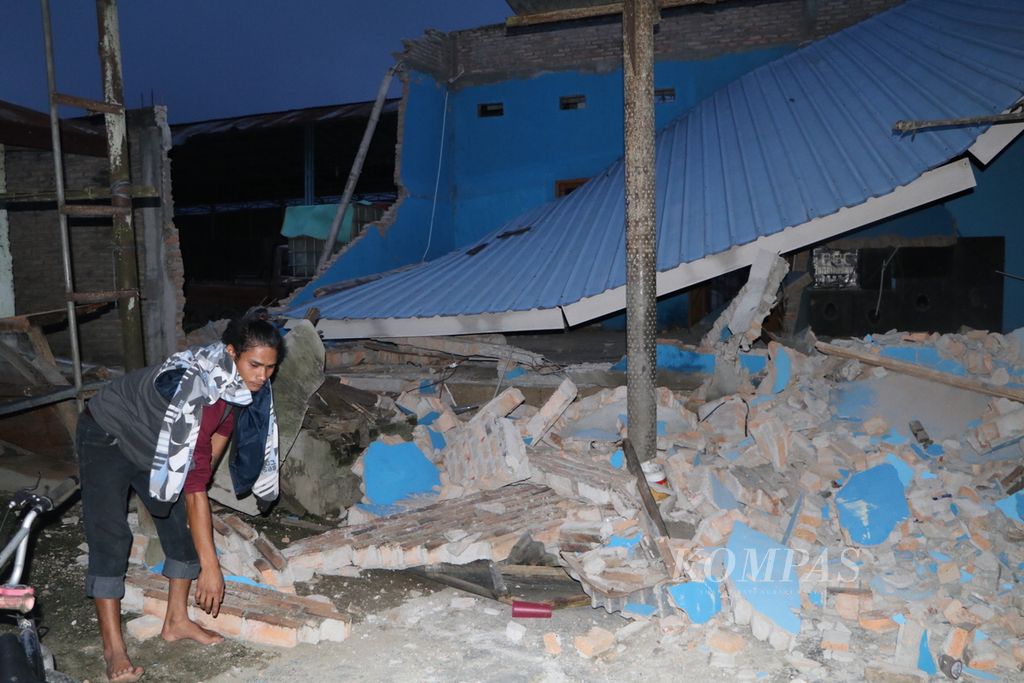 Warga Kecamatan Sipoholon melihat rumah yang roboh akibat gempa bumi berkekuatan M 5,8 di Kabupaten Tapanuli Utara, Sumatera Utara, Sabtu (1/10/2022). Satu orang meninggal, 11 orang terluka, serta sedikitnya 76 rumah dan rumah ibadah rusak akibat gempa itu.