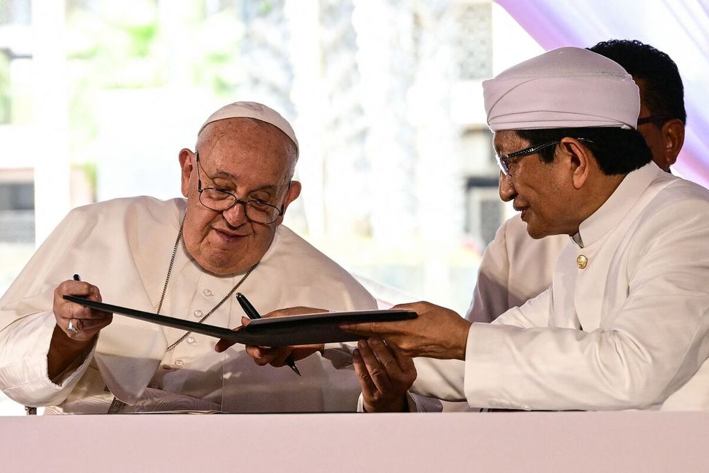 Pope Francis (L) and Grand Imam of Istiqlal Mosque Nasaruddin Umar exchange documents as they sign a declaration during an interreligious meeting with religious leaders at the Istiqlal Mosque in Jakarta on September 5, 2024. (Photo by Tiziana FABI / AFP)