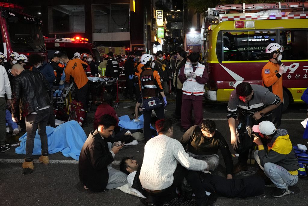  Petugas penyelamat dan pemadam kebakaran membantu para korban di dekat lokasi insiden mematikan pada pesta Halloween di Seoul, Korea Selatan, Minggu (30/10/2022).