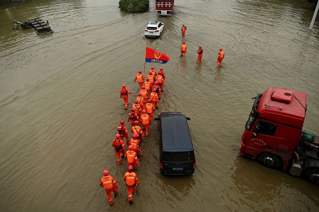 Petugas penyelemat melewati banjir untuk mencari warga yang diduga masih terjebak banjir di Kota Zhengzhou, Henan, China, Jumat (23/7/2021). Banjir membuat permukiman, jalan, kereta bawah tanah, dan pusat bisnis tergenang. AFP/NOEL CELIS