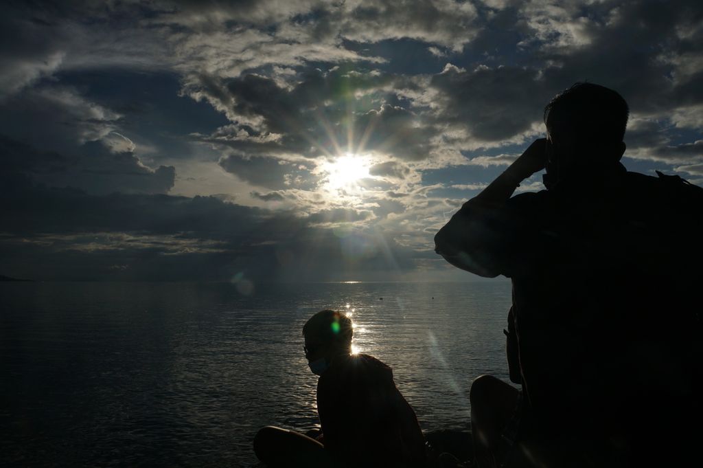 Pengunjung Godbless Park Manado, Sulawesi Utara memotret fenomena gerhana matahari sebagian (GMS) yang tertutup awan pada Minggu (21/6/2020) sore. Gerhana tersebut sebenarnya adalah gerhana matahari cincin (GMC) yang tak tampak sempurna.