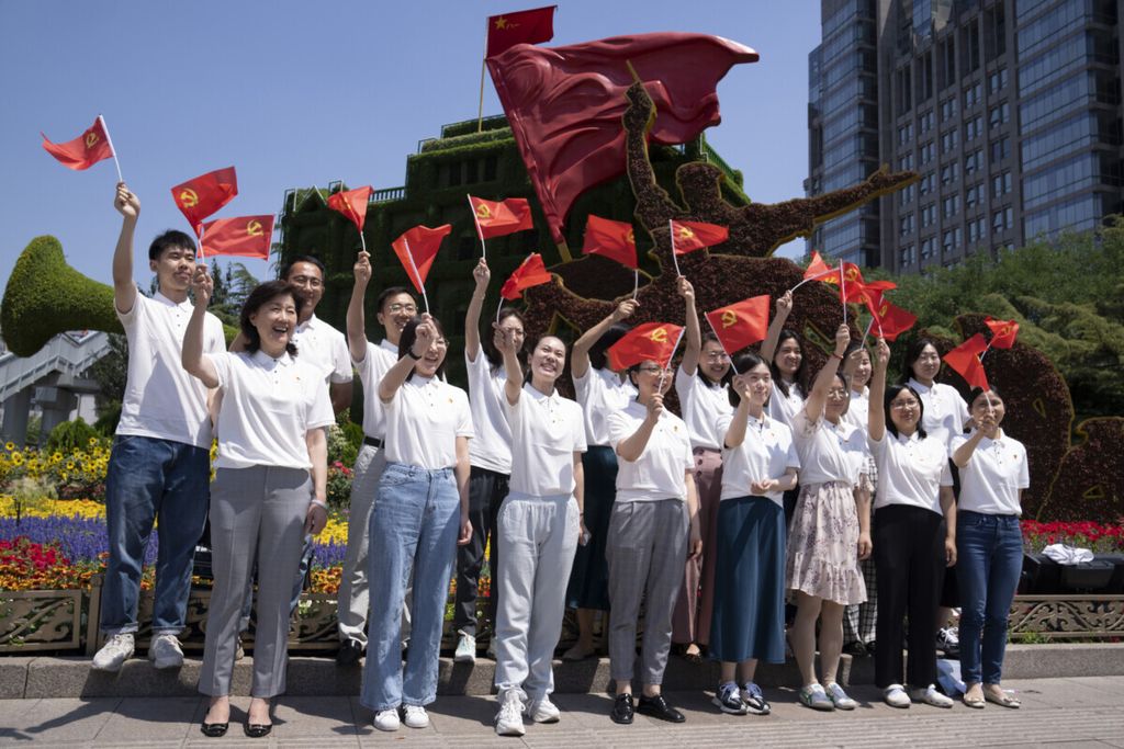 Kader Partai Komunis China mengibarkan bendera saat berpose di depan taman bunga menjelang peringatan 100 tahun berdirinya Partai Komunis China di Beijing, Selasa (22/6/2021). 