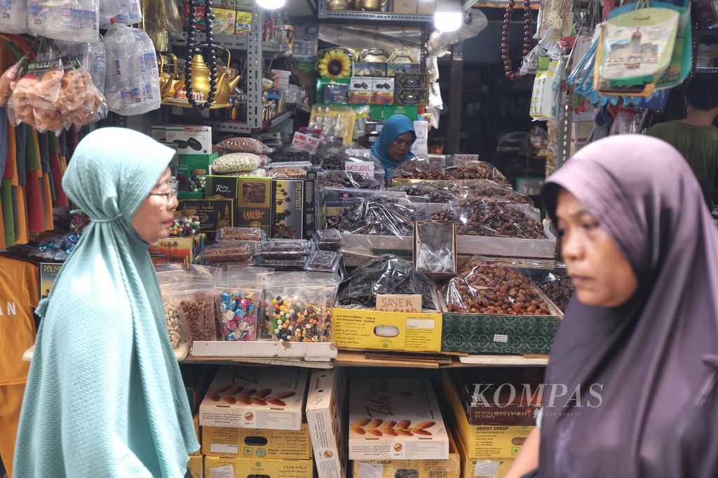 Warga melintas di samping kios pedagang kurma di Pasar Jatinegara, Jakarta, Jumat (8/3/2024).