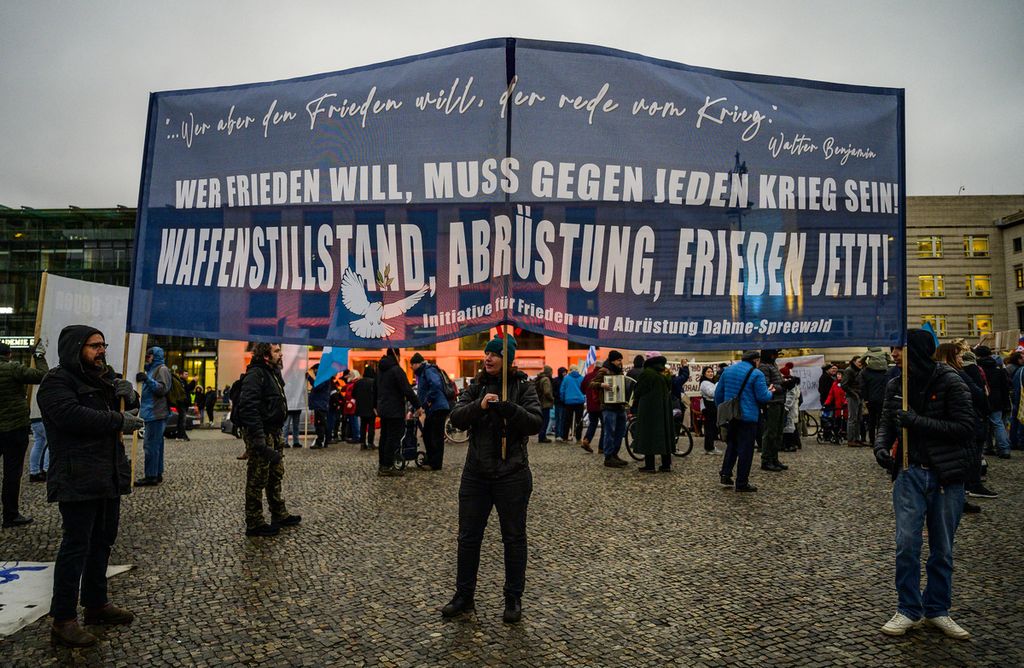 Pengunjuk rasa memegang spanduk yang berbunyi Jika kamu ingin damai, kamu harus melawan setiap perang, gencatan senjata, demiliterisasi, perdamaian sekarangsaat protes di Berlin, Jerman, 24 Februari 2023, menandai setahun invasi Rusia ke Ukraina. 