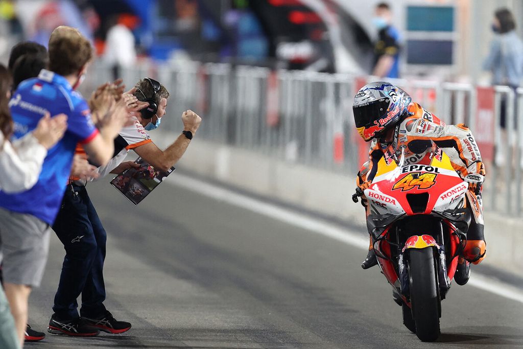 Pebalap Spanyol tim Repsol Honda, Pol Espargaro, merayakan posisi finis ketiga bersama timnya saat melalui lintasan <i>paddock </i>usai seri pertama Grand Prix MotoGP 2022 di Sirkuit Losail, Lusail, Qatar, Minggu (6/3/2022). Espargaro menyelesaikan seri Qatar di belakang Enea Bastianini (Gresini Racing) dan Brad Binder (KTM).